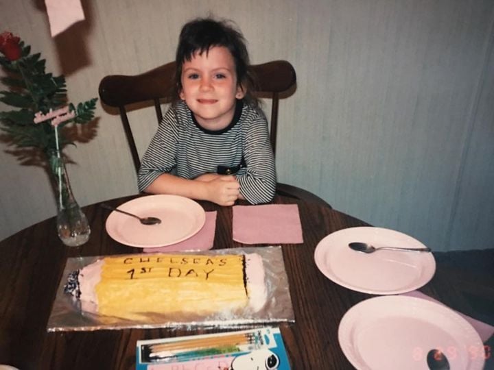 a child sitting at a table with plates and a cake